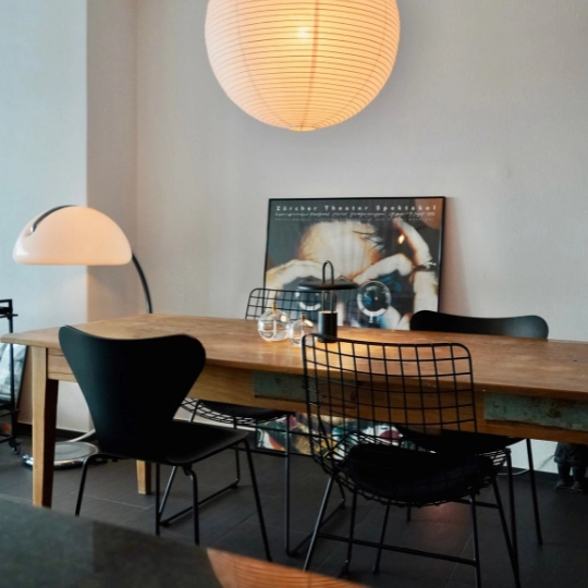 Modernes Esszimmer mit verschiedenen Stühlen. Beleuchtung schafft eine gemütliche Stimmung.