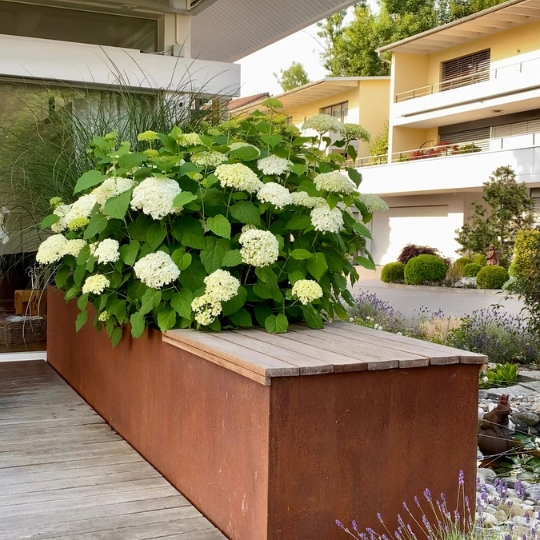 Massgeschneiderte Gartengestaltung mit Hochbeet und Sitzbank.